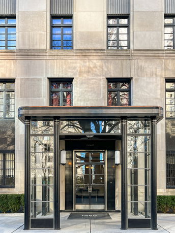 Front view of a multi-story building with an entrance canopy and large windows.