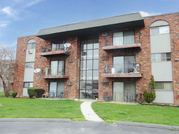 Front view of a multi-story brick apartment building with balconies.