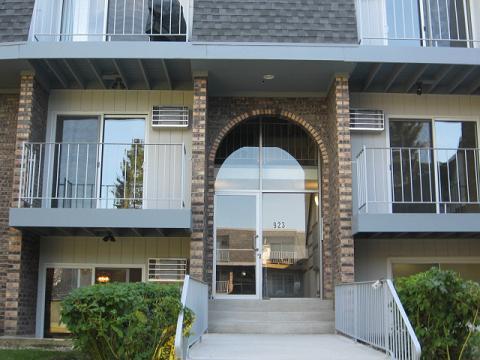 Front view of a multi-story building with balconies and an arched entrance.