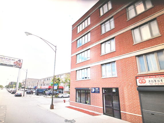 Front view of a multi-story brick building with commercial spaces on the ground floor.