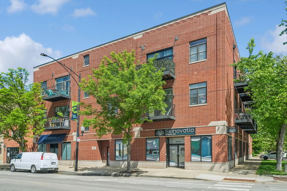 Front view of a multi-story brick building with balconies and a storefront on the ground floor.