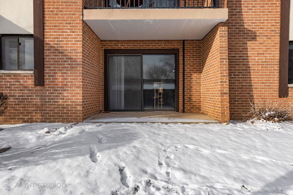 Front view of a brick building with a sliding glass door and balcony.