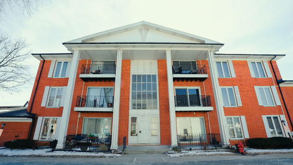 Front view of a three-story building with brick exterior and balconies.