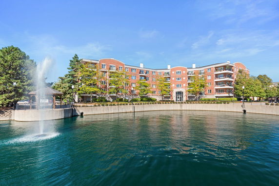 Front view of a multi-story brick building with a fountain in front.