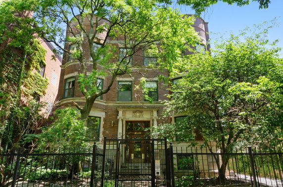 Front view of a multi-story brick building with decorative entrance and wrought iron fence.