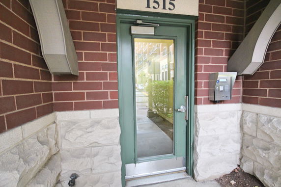 Front view of a building entrance with a green door and keypad entry system.