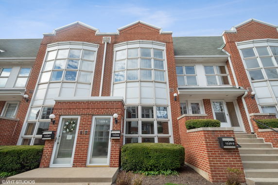 Front view of a multi-story brick townhouse with large bay windows.
