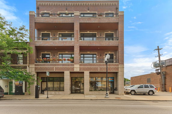 Front view of a multi-story brick building with balconies and large windows.
