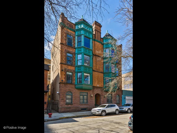 Front view of a multi-story brick building with decorative green accents.