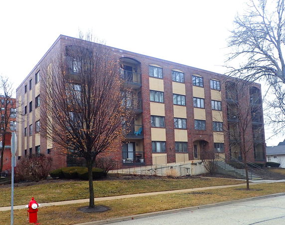 Front view of a multi-story apartment building with a brick facade.