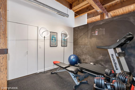 Indoor home gym with treadmill, weights, exercise bench, and a blackboard wall.