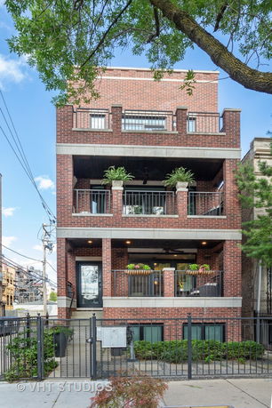 Front view of a three-story brick building with balconies.