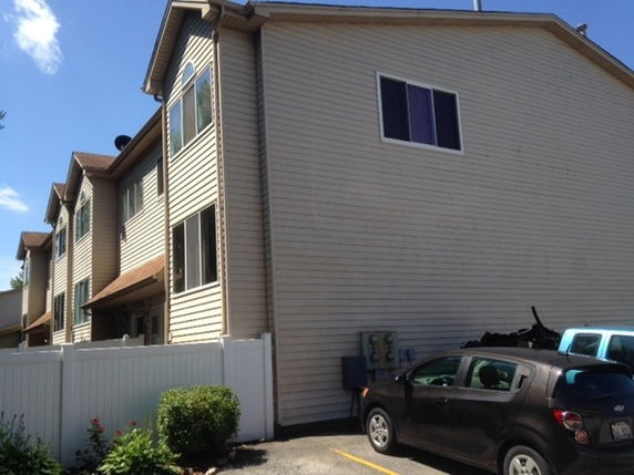 Front view of a multi-story residential building with light-colored siding and multiple windows.