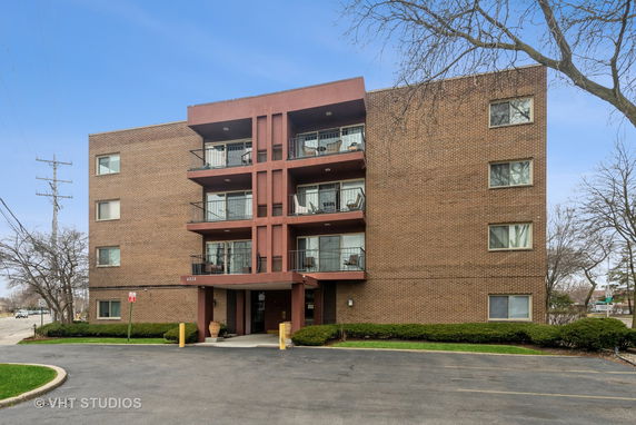 Front view of a multi-story brick apartment building with balconies.