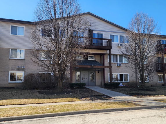 Front view of a three-story residential building with balconies.