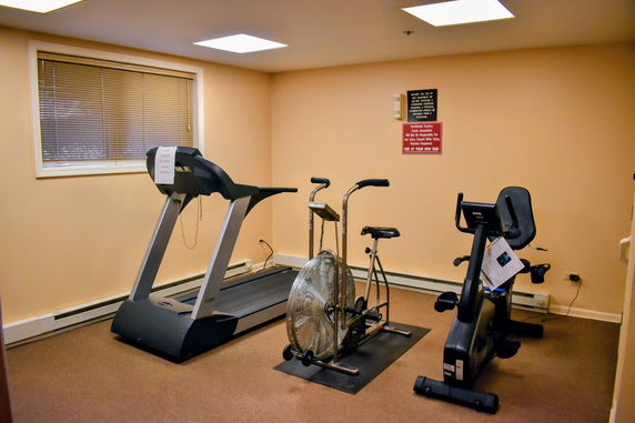 Room with exercise equipment including a treadmill and stationary bike.