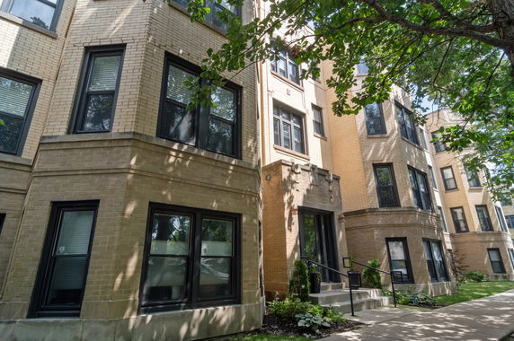 Front view of a multi-story brick apartment building with several windows.