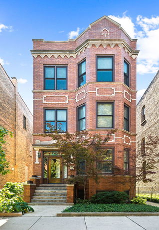 Front view of a three-story brick building with multiple windows.