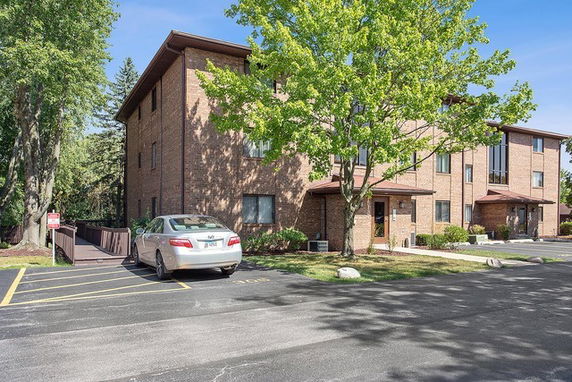 Front view of a multi-story brick building with a parking area.