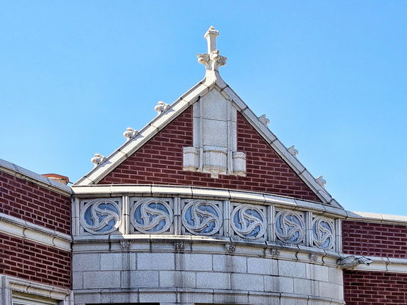 Front view of a building with intricate brick and stonework featuring decorative elements on the roof.