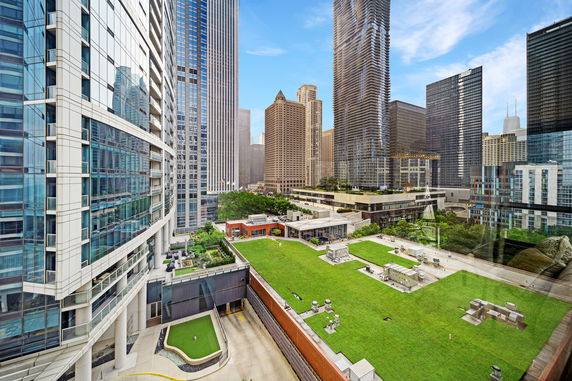 View of a cityscape including several high-rise buildings with a rooftop garden and mechanical equipment.