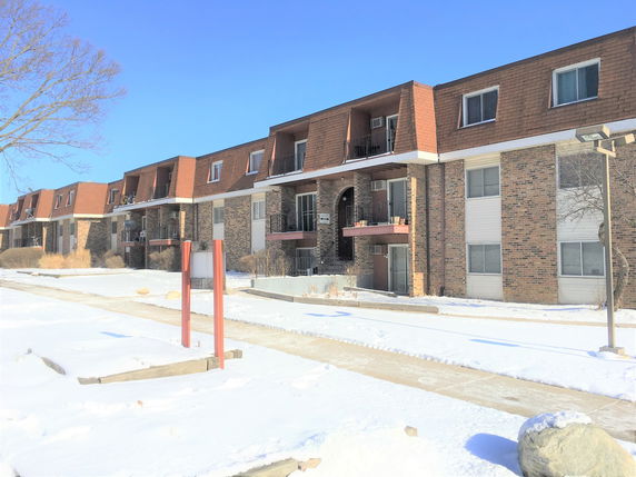 Front view of a multi-story residential building with balconies and brick exterior.