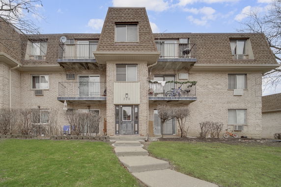Front view of a three-story residential building with balconies and a main entrance.