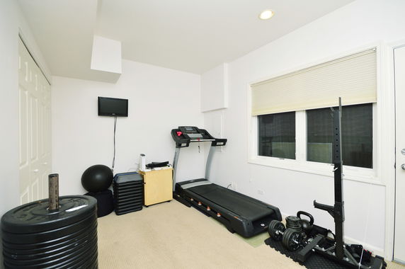 Indoor gym area with exercise equipment including a treadmill, weights, and exercise ball.