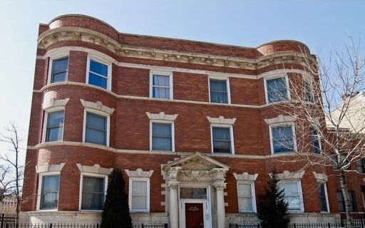 Front view of a three-story brick building with decorative windows.