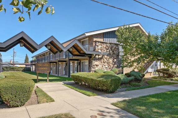 Front view of a two-story condo complex with a unique roof design.