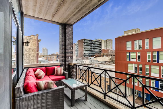 Balcony view overlooking city buildings with outdoor seating.