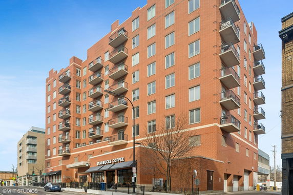 Front view of a multi-story brick building with retail spaces on the ground floor.