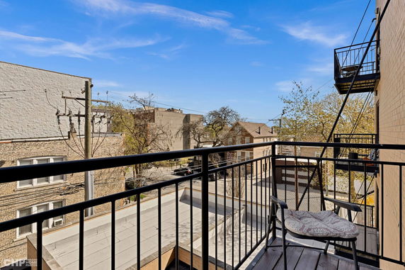 A view from a balcony overlooking buildings and trees in an urban area.