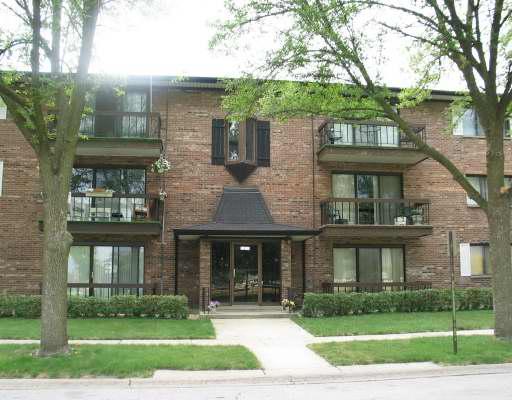 Front view of a multi-story brick apartment building with balconies.