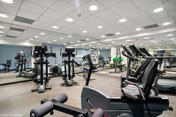 Interior view of a fitness center with exercise equipment and mirrors.