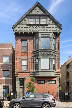 Front view of a multi-story brick building with decorative windows and a gabled roof.