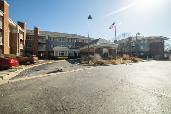 Front view of a multi-story building with an entrance canopy and parking area.