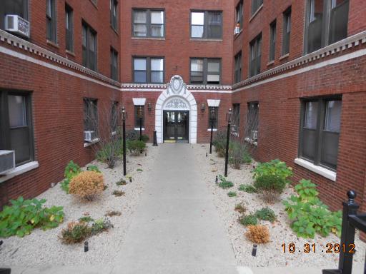 Front view of a red brick apartment building with an arched entrance.