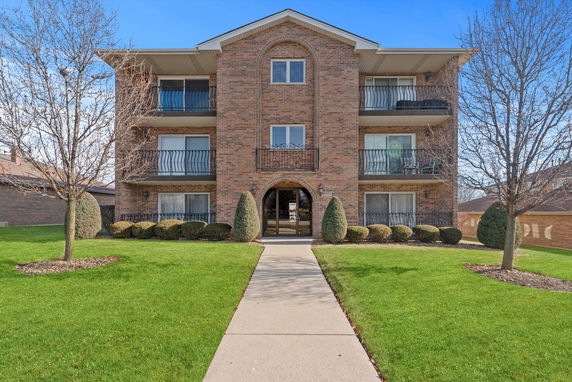 Front view of a multi-story brick apartment building with balconies.