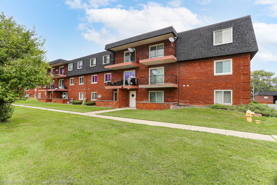 Front view of a multi-story brick apartment building with balconies.