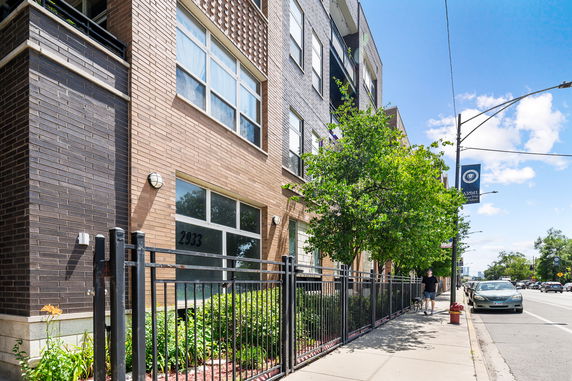 Front view of a multi-story building with brick facade and large windows.