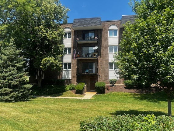 Front view of a multi-story brick apartment building with balconies.