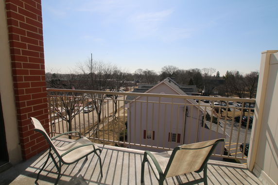 View from a balcony with chairs overlooking nearby houses and trees.