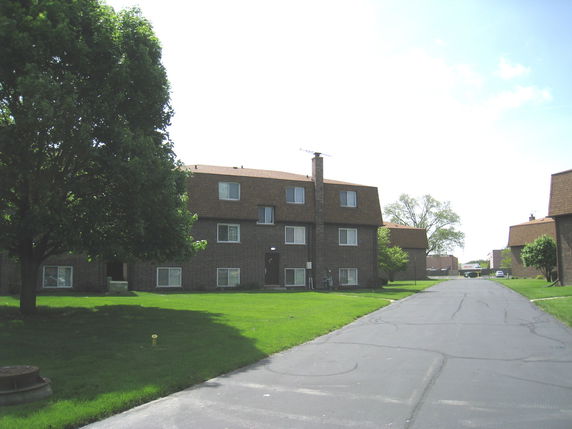 Front view of a multi-story brick apartment building with a sloped roof.