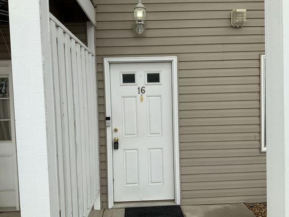 Front view of a house entrance with a white door and siding.