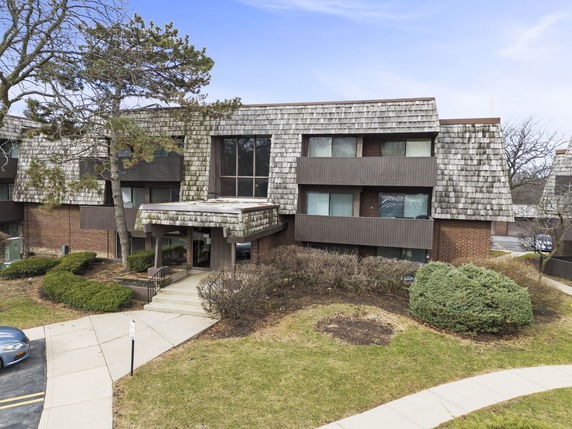 Front view of a multi-story building with shingle roofing and brick facade.