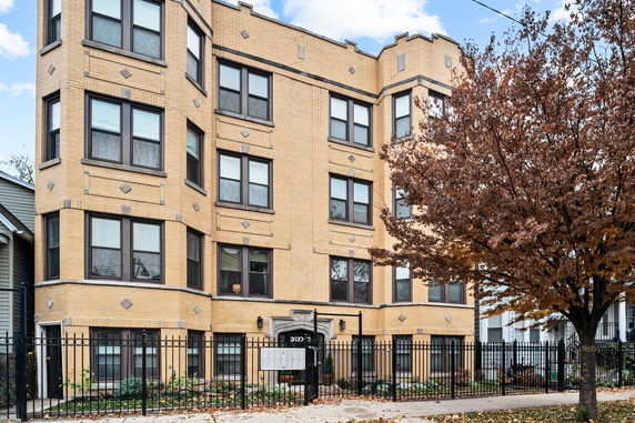 Front view of a multi-story brick apartment building with numerous windows.