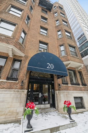 Front view of a brick apartment building with a blue canopy entrance.