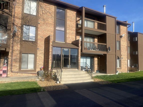 Front view of a multi-story apartment building with balconies and large windows.