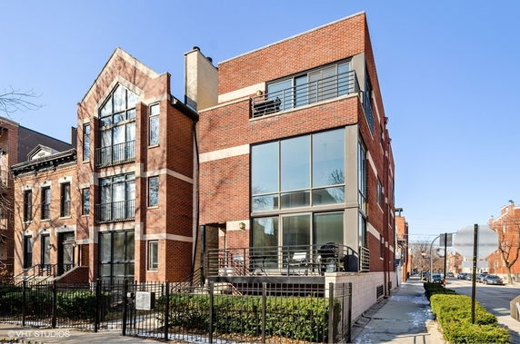 Front view of a modern multi-story brick building with large windows and balconies.